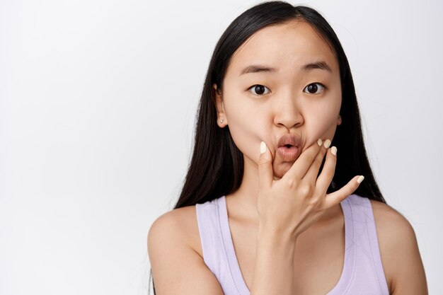 Silly young asian woman poking and sqeezing her face pucker lips cute making funny adorable facial expression white background