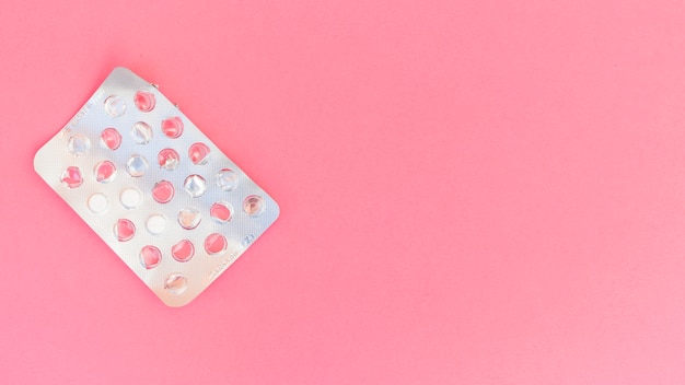 Silver blister pack of pills on pink background