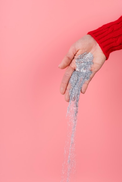 Silver glitter held in hand on pink background