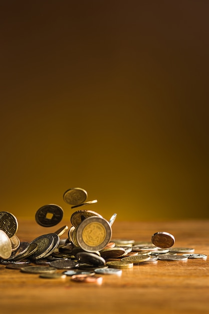 Free photo the silver and golden coins and falling coins on wooden table