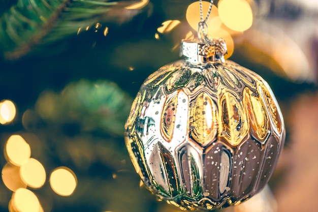 Free photo silver shiny christmas ball on a christmas tree branch closeup