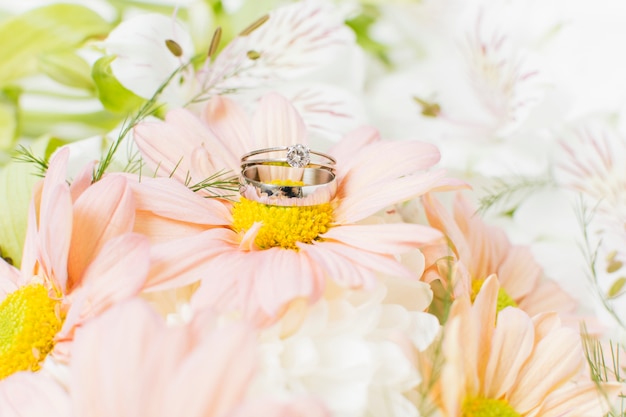 Silver wedding rings on pink gerbera flower bouquet