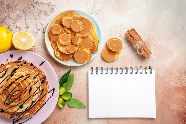 Simple and decorated classic pancakes with fruits and notebook