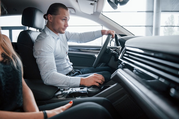 Free photo simple and nice interior. positive manager showing features of the new car to female customer