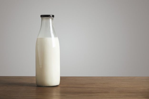 Free photo simple vintage bottle filled with fresh milk on thick wooden table. closed with black cap. cafe shop