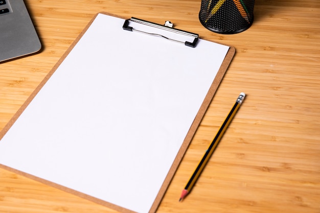 Free photo simple wood desk with clipboard and pen