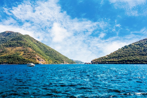 Single boat over the blue calm lake near the green mountain