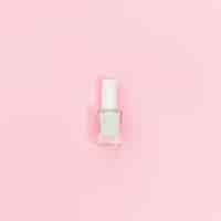 Free photo single bottle of white nail polish on pink background