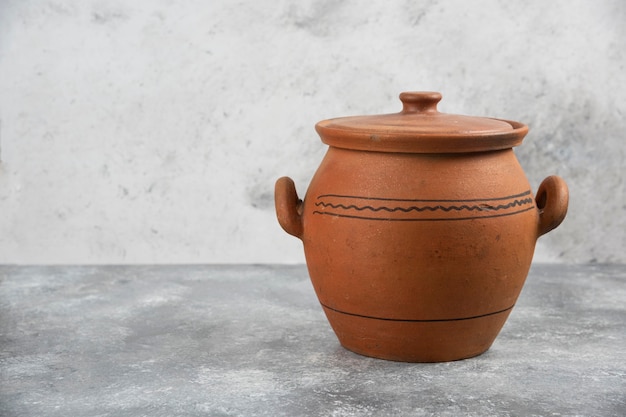 Single clay antique vase placed on marble surface.