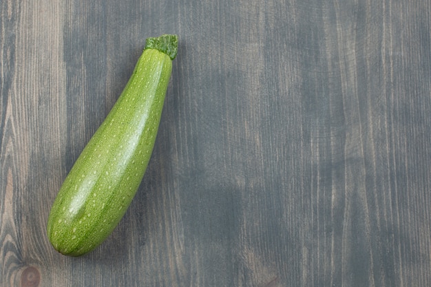 Free photo single courgette or zucchini isolated on a wooden table