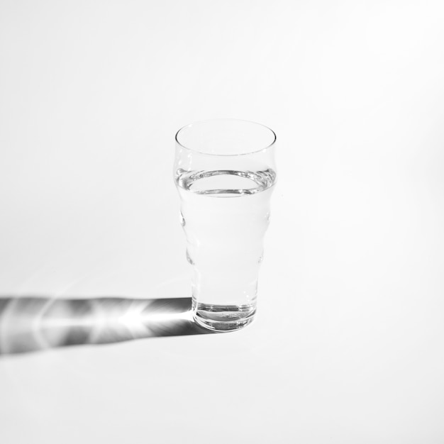 Single glass of water with bright shadow isolated on white background