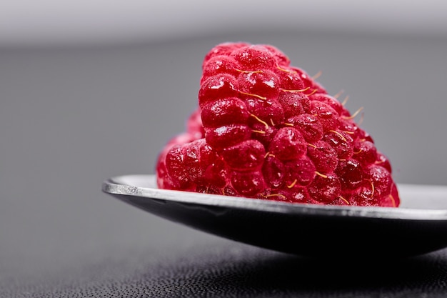 Free Photo single large raspberry on spoon. close up. 