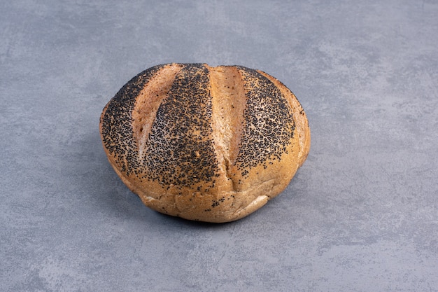 Single loaf of black sesame coated bread on marble.