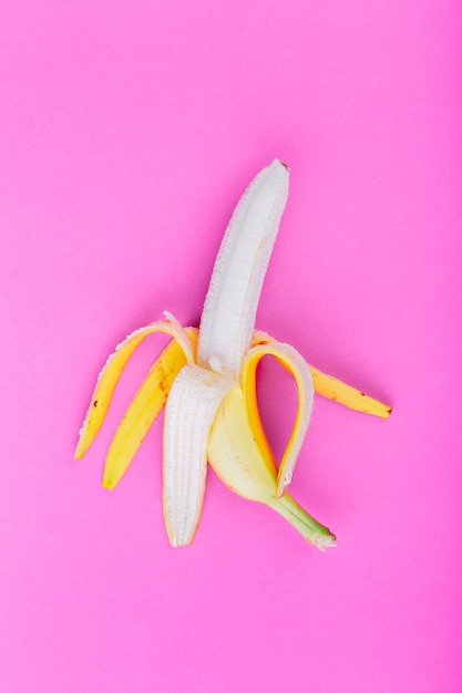 Free photo single peeled banana on pink background