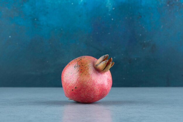 Single red pomegranate on marble.