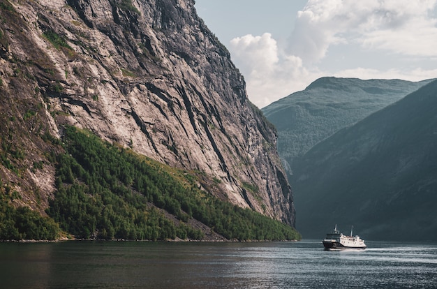 Free photo single ship in the lake surrounded by high rocky mountains under the cloudy sky in norway