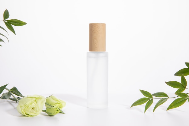 Single skincare bottle on a white background with a rose and green leaves