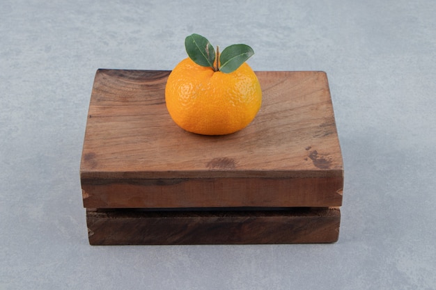 Free photo single tasty clementine on wooden box.