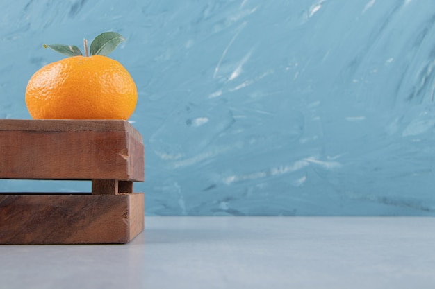 Free Photo single tasty clementine on wooden box