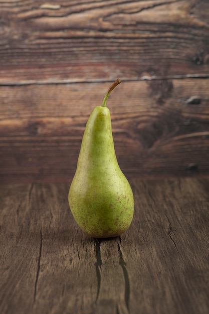 Single tasty fresh pear placed on wooden surface