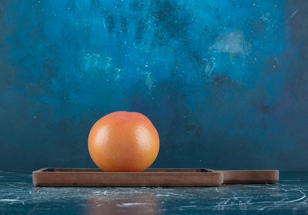 Single tasty orange on wooden board. 