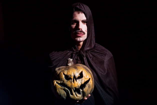 Free Photo sinister man with scary pumpkin