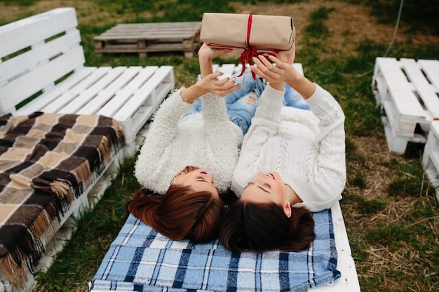 Free photo sisters lying down holding a present