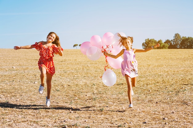 Free photo sisters running with balloons