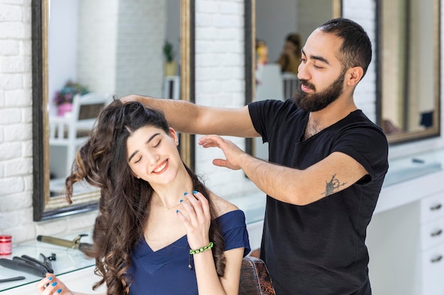 Sitting at the barbershop and smiling while Barber making her hair High quality photo