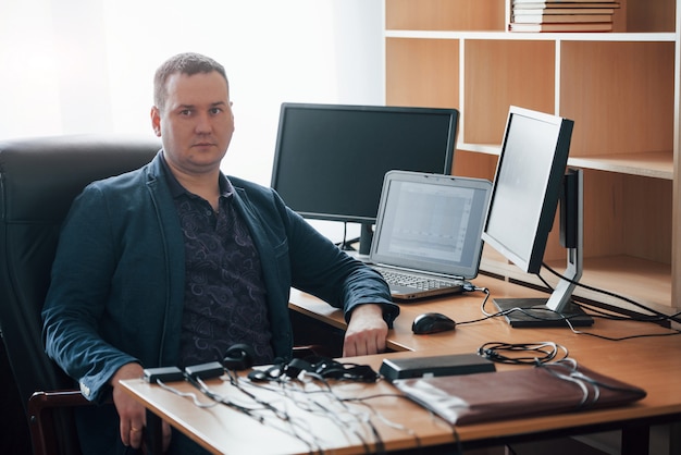 Sitting on the black chair. Polygraph examiner works in the office with his lie detector's equipment