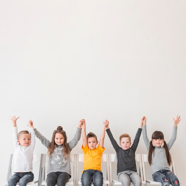 Free Photo sitting children with their hands up