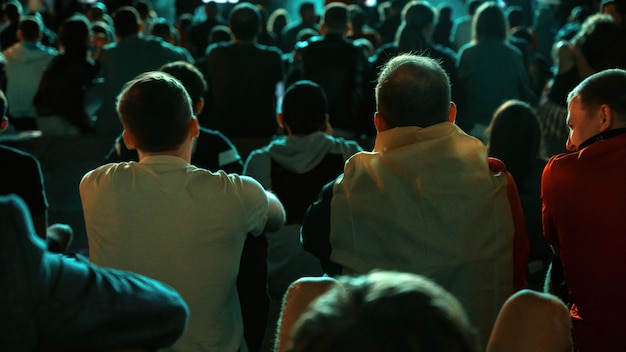 Sitting people watching football in a public place at night