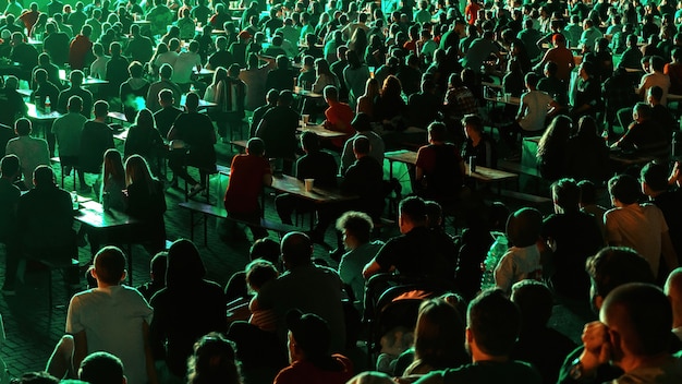 Sitting people watching football in a public place at night