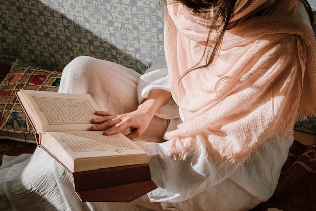 Free photo sitting woman reading in quran