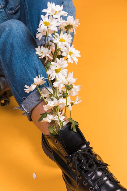 Sitting womans legs in boots with flowers bouquet inside 