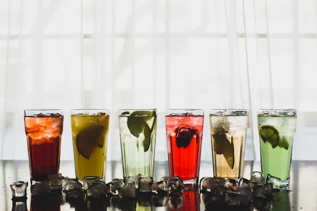 Free photo six glasses of fruit cocktails surrounded with ice cubes