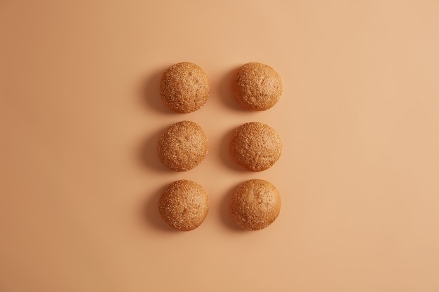 Free Photo six sesame burger buns arranged in two rows on beige studio background. homemade brioche used as dinner rolls. bread cooked at home by chef. delicious food for breakfast. overhead high angle view