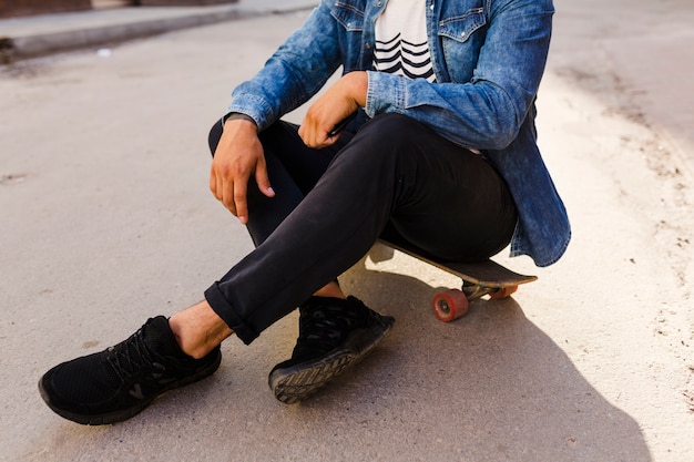 Free photo skateboarder sitting on skateboard