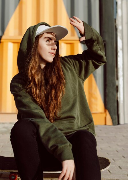 Skater girl hiding her face from the sun with her head