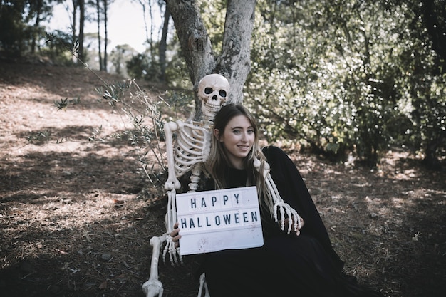 Free Photo skeleton embracing smiling lady with tablet in dark suit