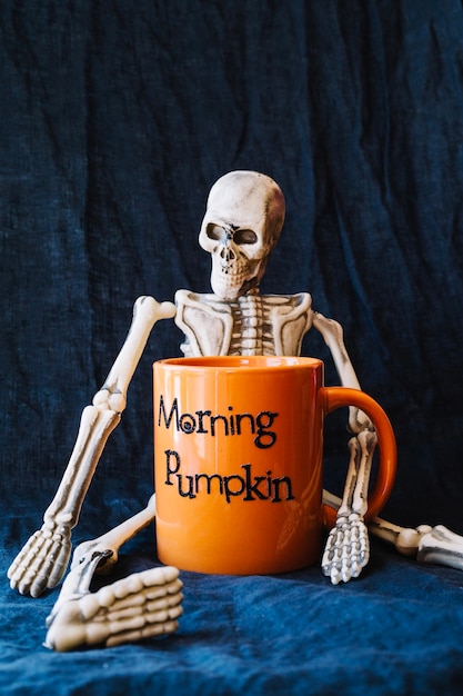 Free photo skeleton with orange mug