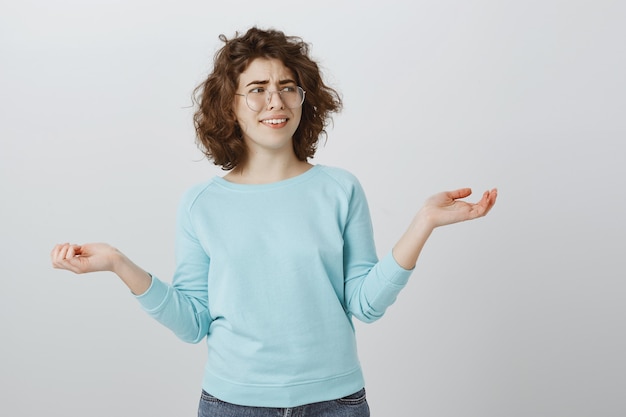 Free photo skeptical unbothered girl smiling and raising hands sideways careless