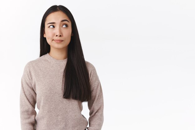 Skeptical, unsure attractive asian woman with long dark hair, have doubts and hesitation, making choice with uncertain expression, smirk bothered look suspicious upper right corner, concerned