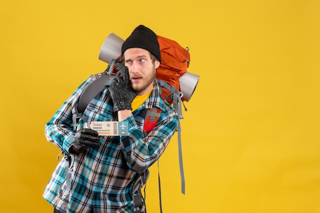 Free Photo skeptical young backpacker with black hat holding airplane ticket