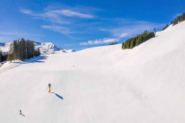 Free Photo ski area with skiers sliding down the snow-covered slope under a blue sky