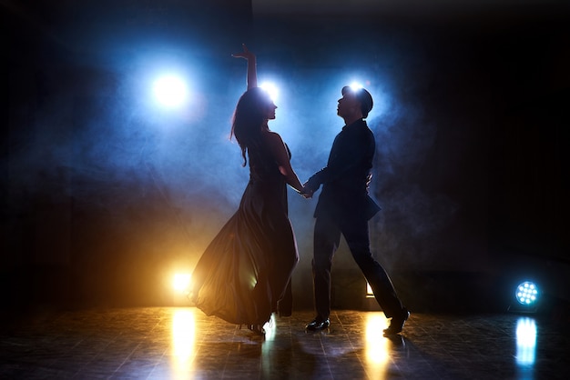 Free Photo skillful dancers performing in the dark room under the concert light and smoke. sensual couple performing an artistic and emotional contemporary dance