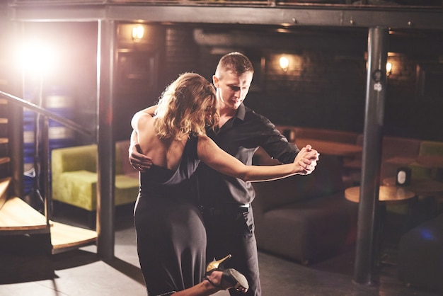 Free photo skillful dancers performing in dark room under light.