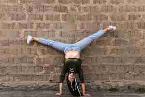 Free photo skillful female dancer doing hand stand stretching her leg