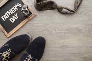 Free photo slate, necktie and shoes on wooden surface for father's day