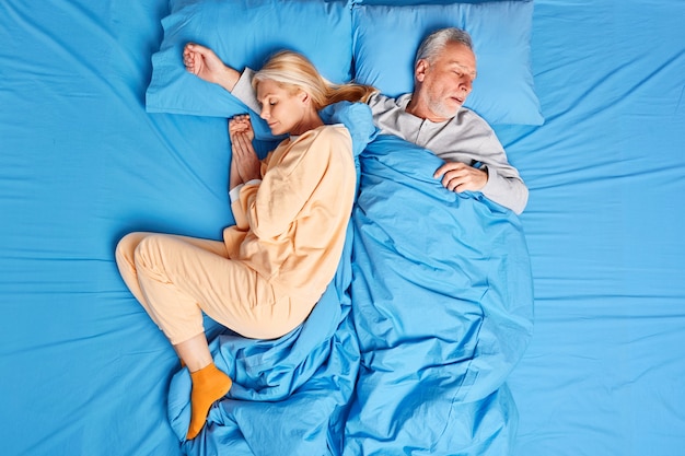 Sleeping married family couple have deep sleep at night enjoys serene atmosphere dressed in nightwear. Mature woman and man take nap after hard working day feel comfortable. Bedtime concept.